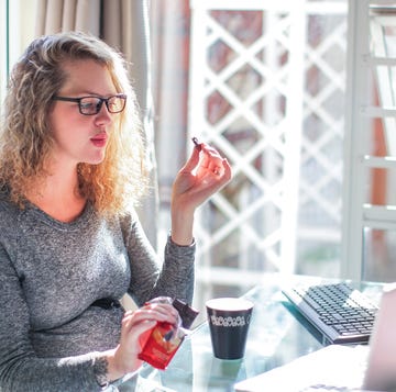 a young pregnant woman eating chocolate at her desk at work