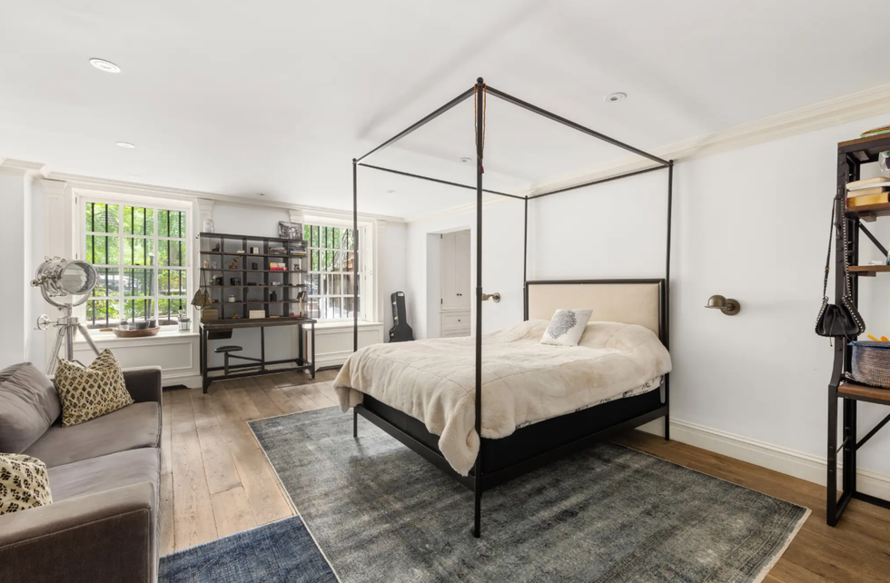 Modern bedroom featuring a canopy bed and a cozy seating area.