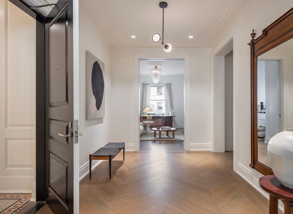 Entrance to one of the units in the Belnord building with chevron-style white oak accent floors, high gloss lacquered entry doors and custom moldings