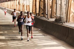 a group of runners is in action on a bridge