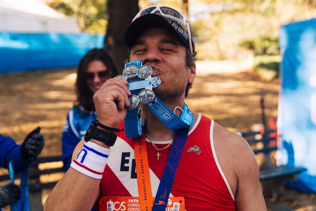 participant celebrating achievement with medals and bib abbott world majors six star finisher