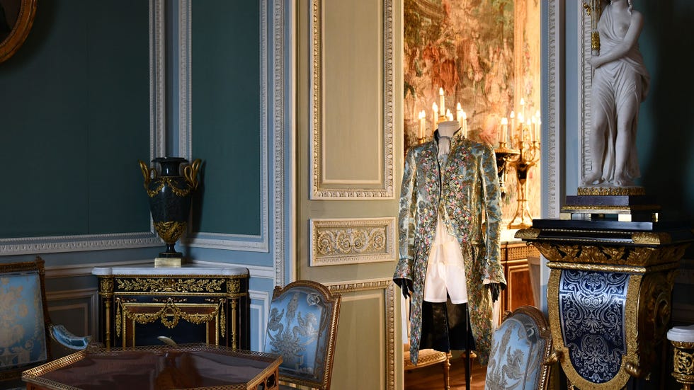 A historical room featuring an ornate costume display and lavish decor.