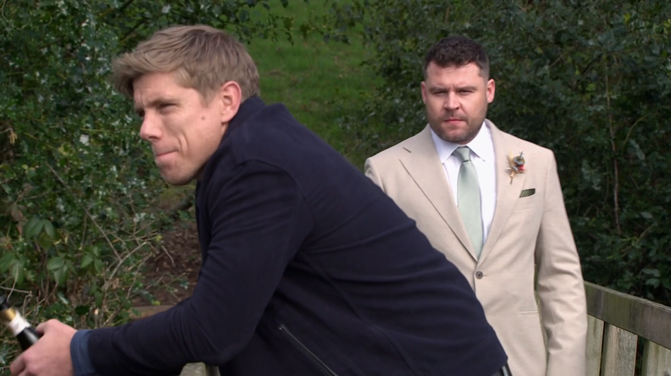 emmerdale characters robert sugden and aaron sugden chatting on a bridge