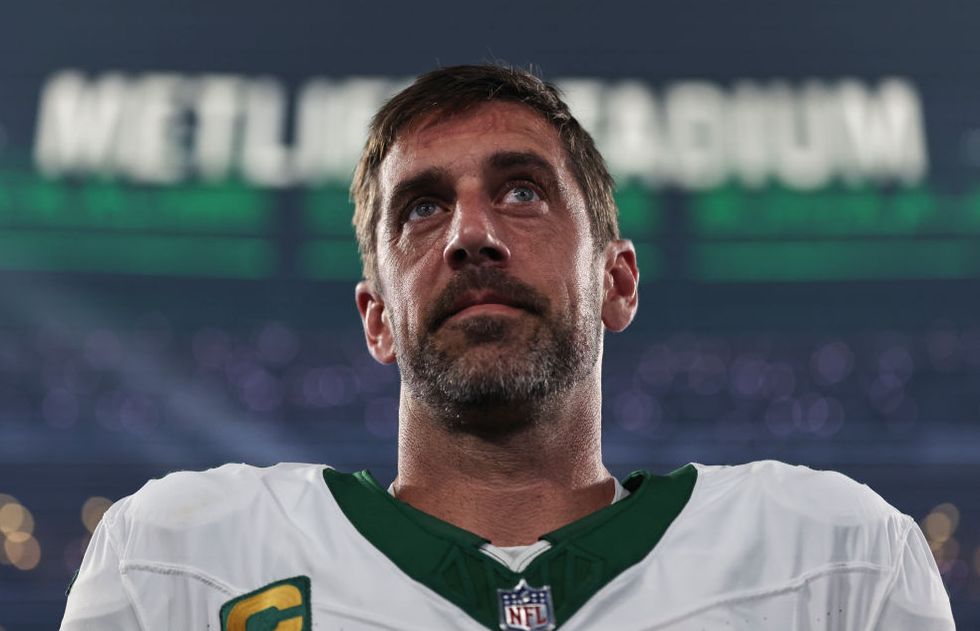 aaron rodgers looking toward the sky while stnading in his jets uniform