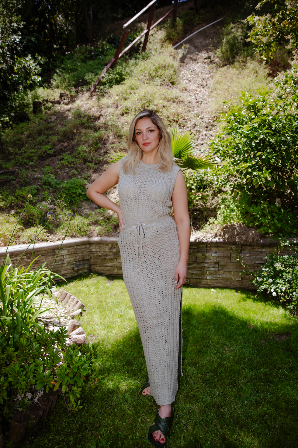 abby elliott bahçede hafif örme bir elbise giyiyor