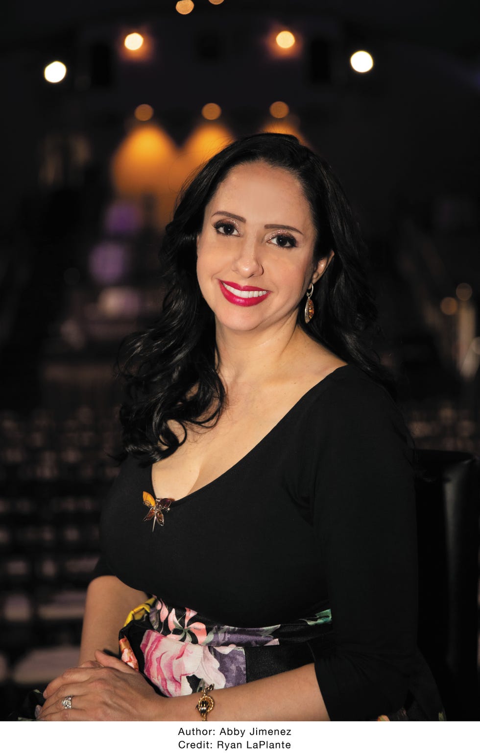 romance novelist abby jimenez in a black top and floral skirt