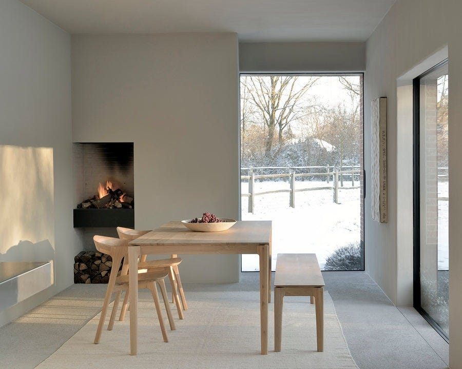 dining area featuring a modern table benches and a fireplace with a snowy outdoor landscape visible through large windows