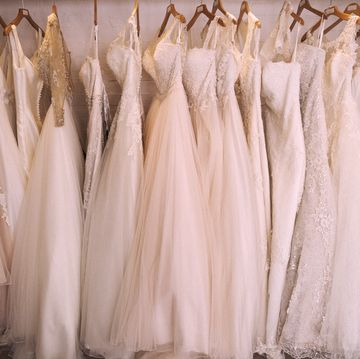 Rows of wedding dresses on display in a specialist wedding dress shop. A variety of colour tones and styles, fashionable lace and boned bodices.