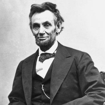 president abraham lincoln stares into the camera with a slight smile in this black and white photo, he wears a dark colored tuxedo