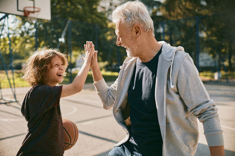un adulto y un niño chocan la mano en una pista de baloncesto