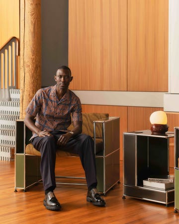 a person sitting on a green armchair next to a side table