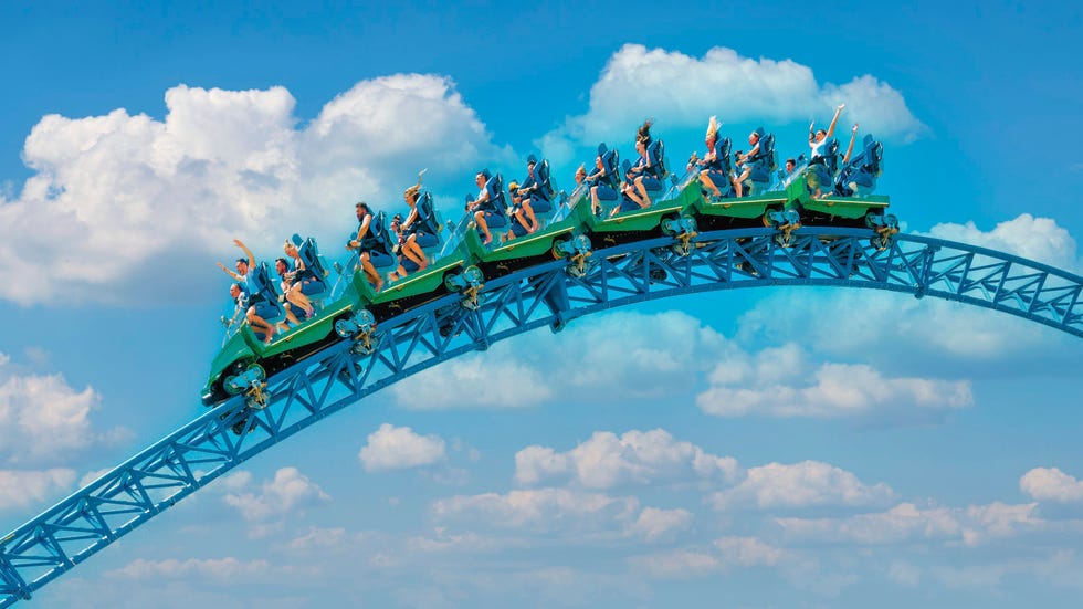 roller coaster with riders at the peak of a loop against a blue sky