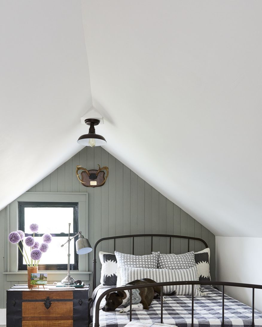 attic bedroom with gray green wall and black iron bed