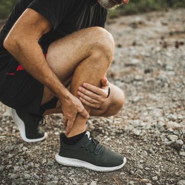 achilles muscle injury on running outdoors. senior man holding knee by hands and suffering with pain. sprain ligament.