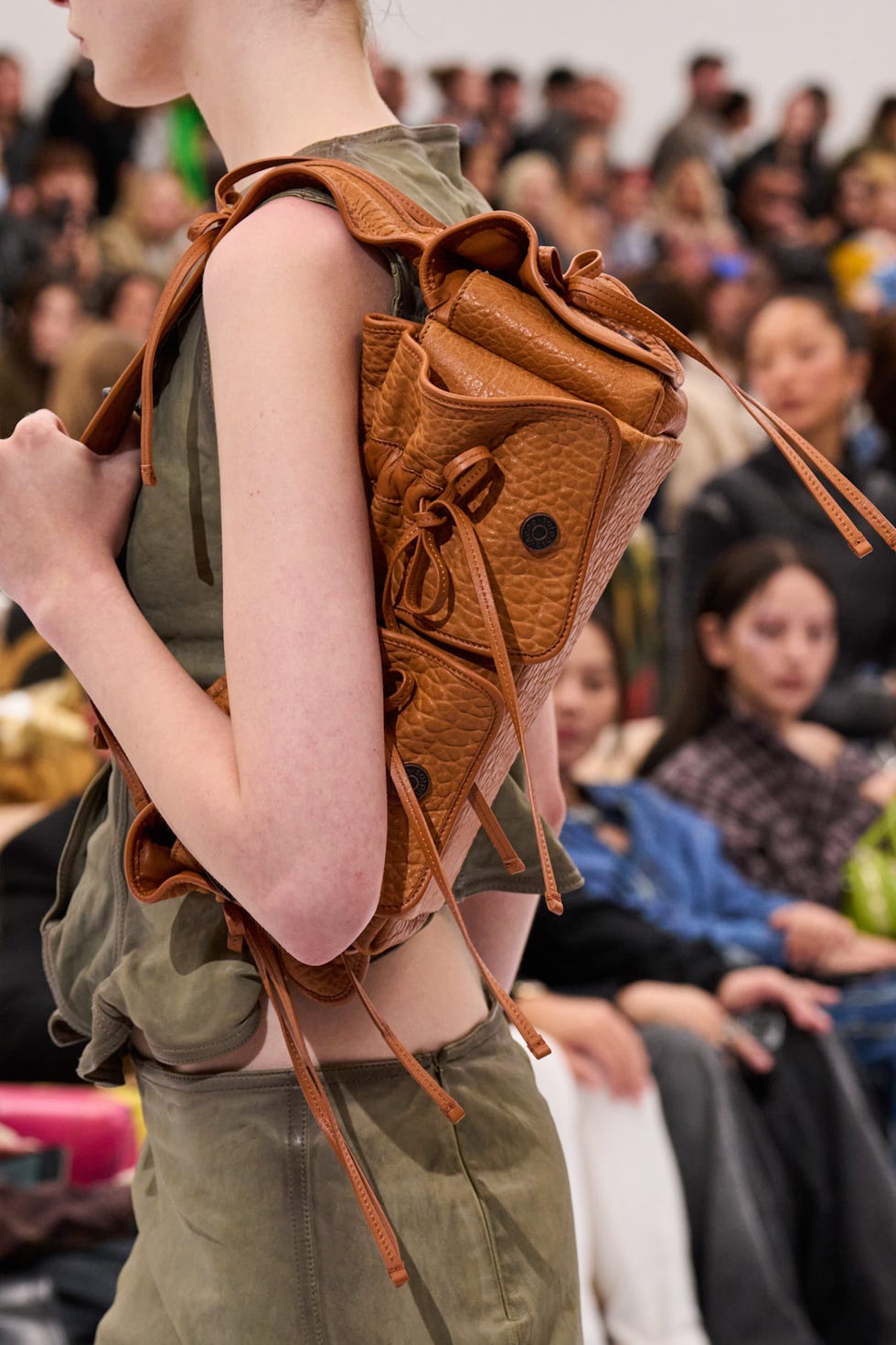 Model showcasing a brown leather backpack at a fashion event