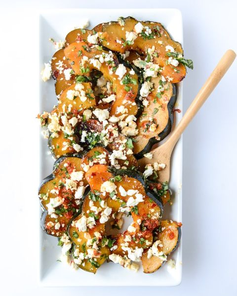 spicy acorn squash with feta and herbs and wooden spoon