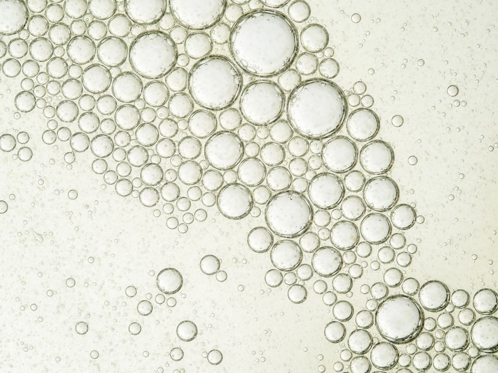 Oil drops and bubbles floating over water with a white background