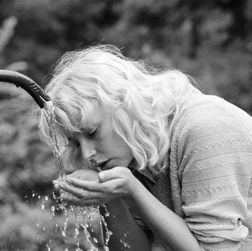 germany out eighties, black and white photo, people, young woman drinking water from a spring, refreshment, cooling, portrait, blond, 30 to 35 years, elizabeth photo by werner otto\ullstein bild via getty images