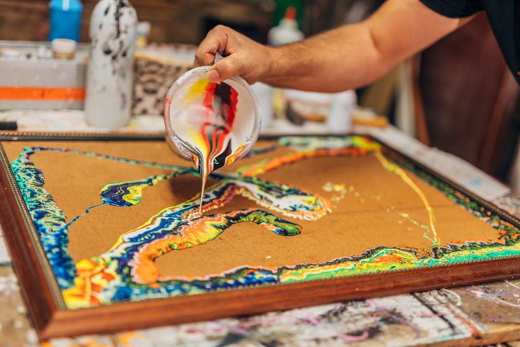 artist pours mixed colors on a canvas