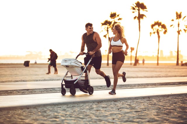 active and sportive family running by the beach with their baby