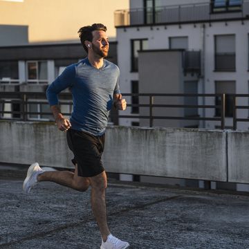 active man running near railing on terrace at sunset