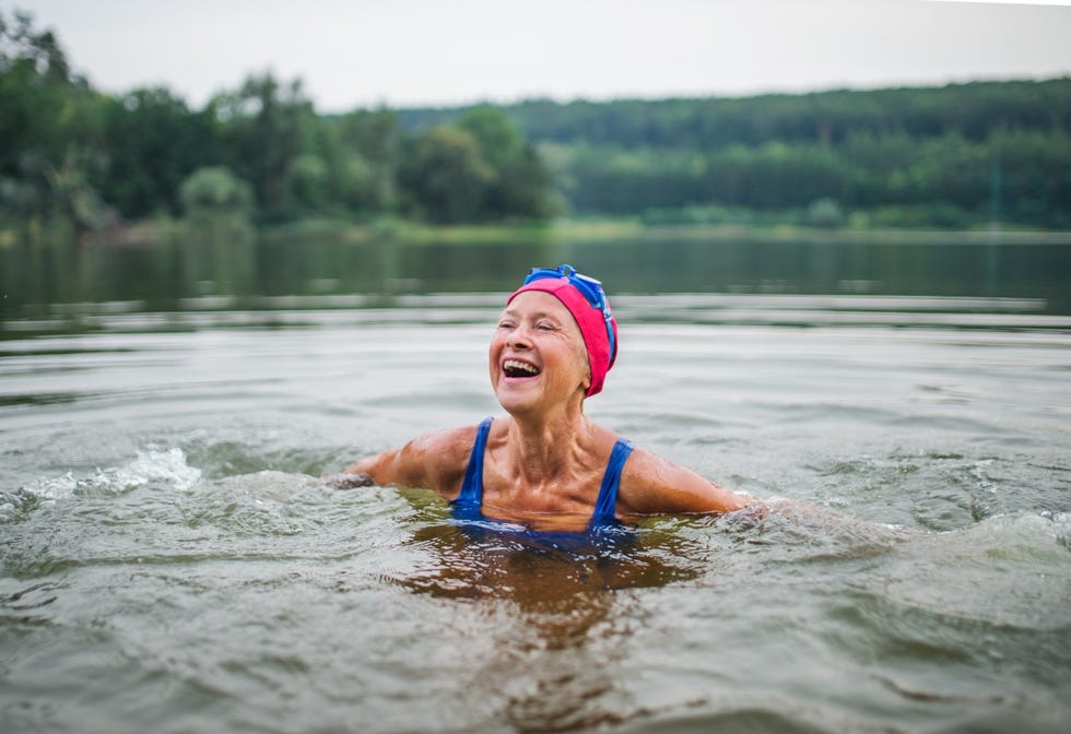 mujer mayor en medio de un lago, sonriendo
