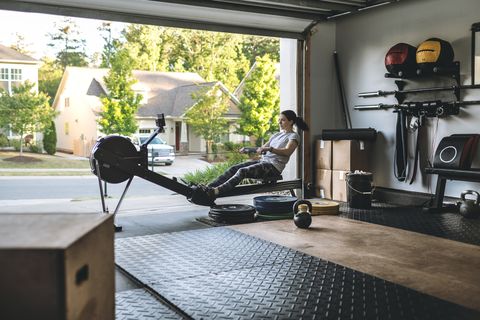 active woman exercising on a rowing machine in her home garage gym during covid 19 pandemic