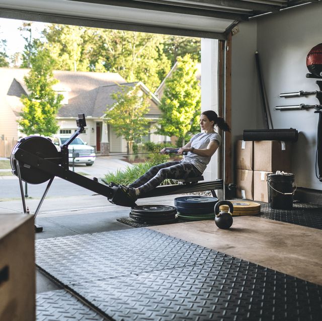 home gym equipment active woman exercising on a rowing machine in her home garage gym during covid 19 pandemic