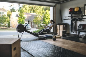 home gym equipment active woman exercising on a rowing machine in her home garage gym during covid 19 pandemic