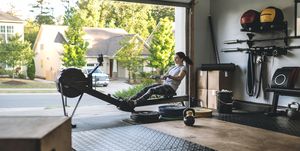 home gym equipment active woman exercising on a rowing machine in her home garage gym during covid 19 pandemic