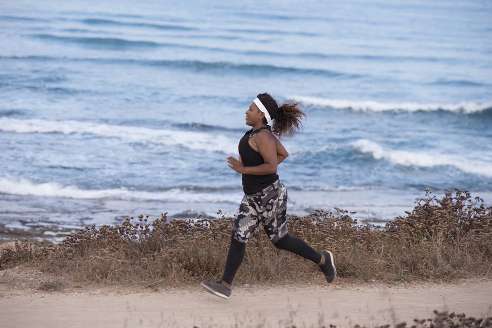 Active woman running on outdoors track near to coastline.