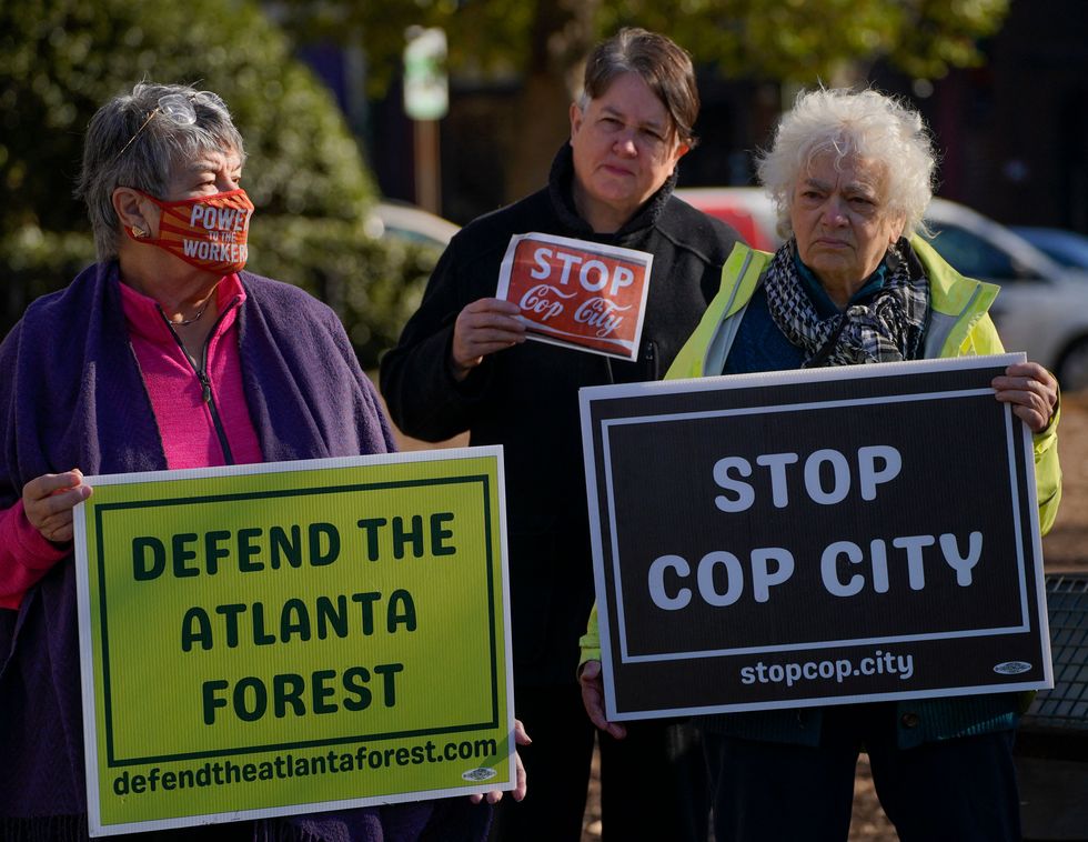 activists hold signs that read defend the atlanta forest and stop cop city