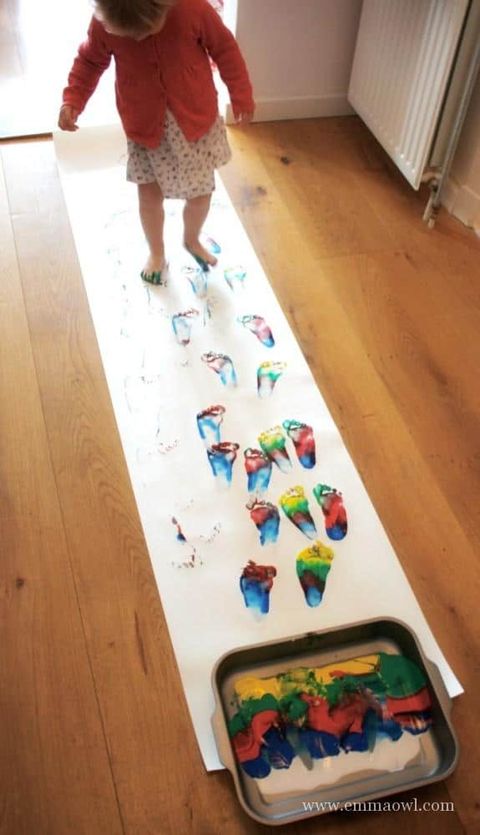 a roll of paper is studed with rainbow footprints after a rainbow walking activity the project is a good housekeeping pick for best activities for kids