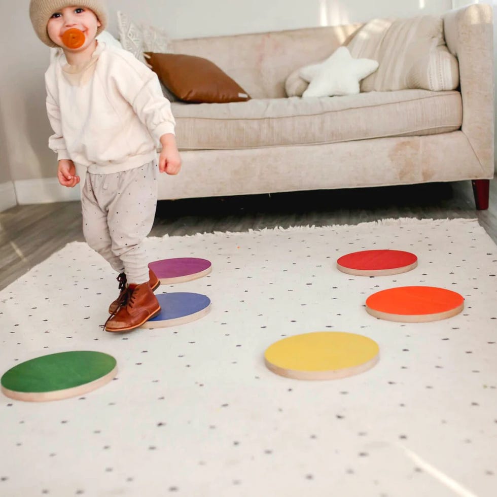 a toddler walks on rainbowcolored stepping stones