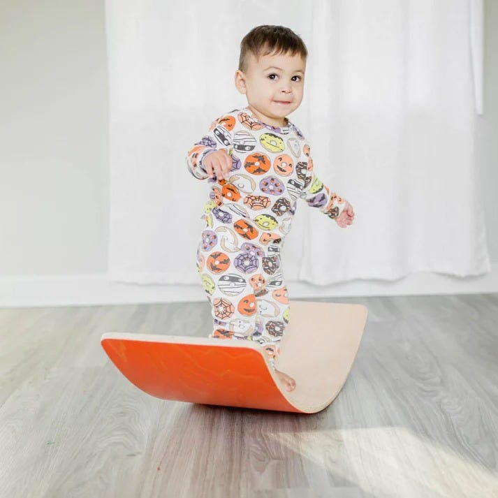 a kid balances on a bunny hopkins wobble board