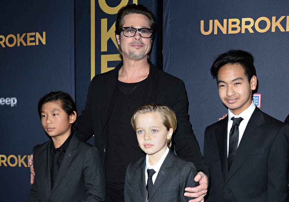 pax jolie pitt, brad pitt, shiloh jolie pitt, and maddox jolie pitt stand together and pose for photos in formal attire