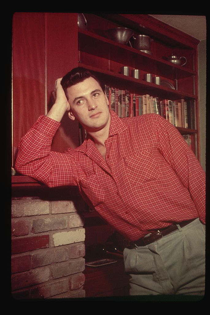 rock hudson leaning on a fireplace mantle
