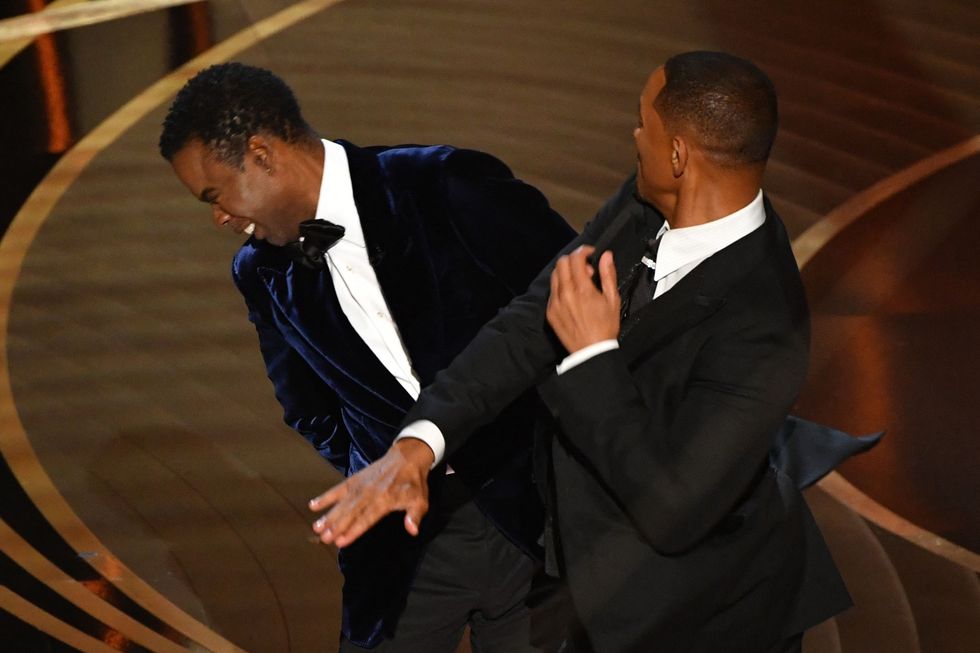 will smith slapping chris rock across the face on a stage, with both men wearing black tuxedos