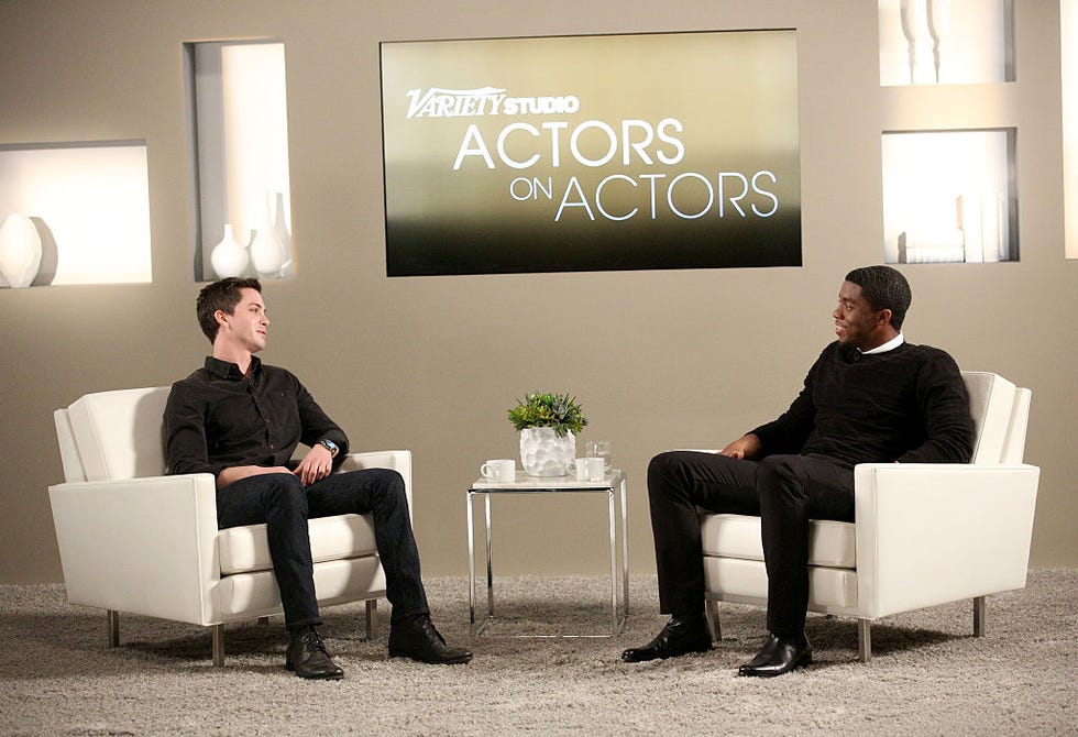 logan lerman and chadwick boseman sit in white armchairs