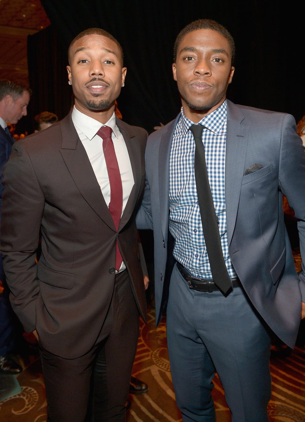 michael b jordan and chadwick boseman pose for a photo, both men wear suits with ties
