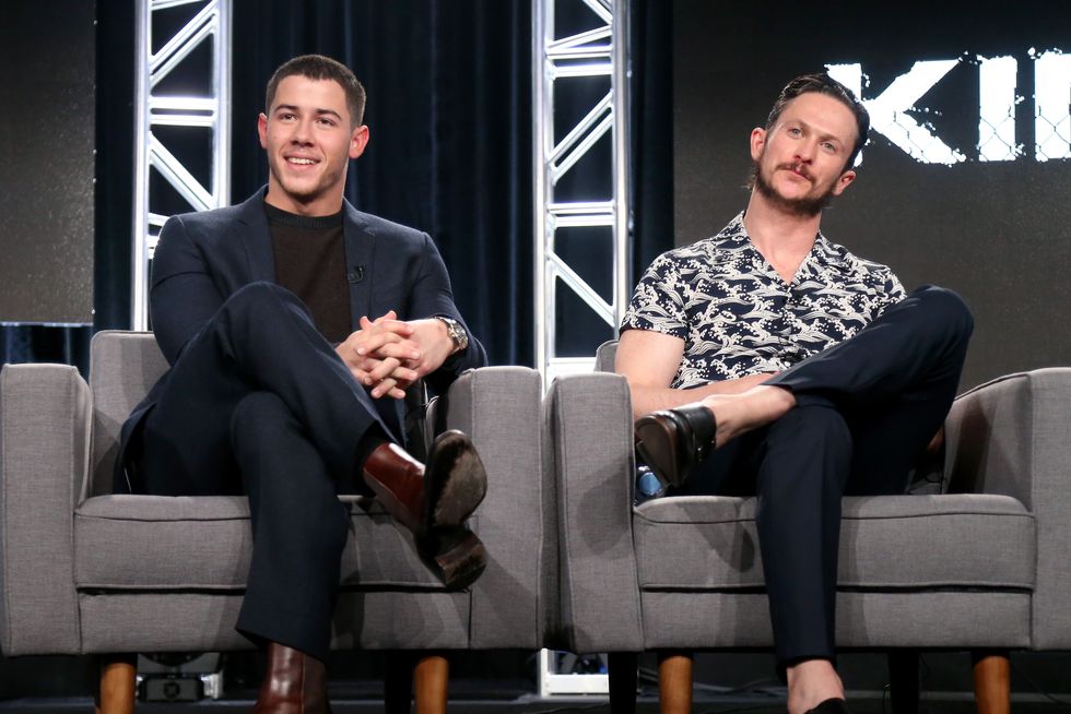 nick jonas sits onstage with jonathan tucker