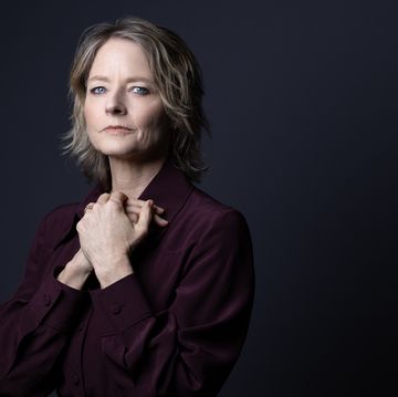 a person wearing a red blouse poses for a portrait against a dark background