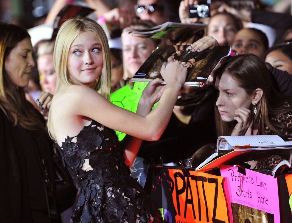 dakota fanning signing autographs as she turns her head back to look out of frame