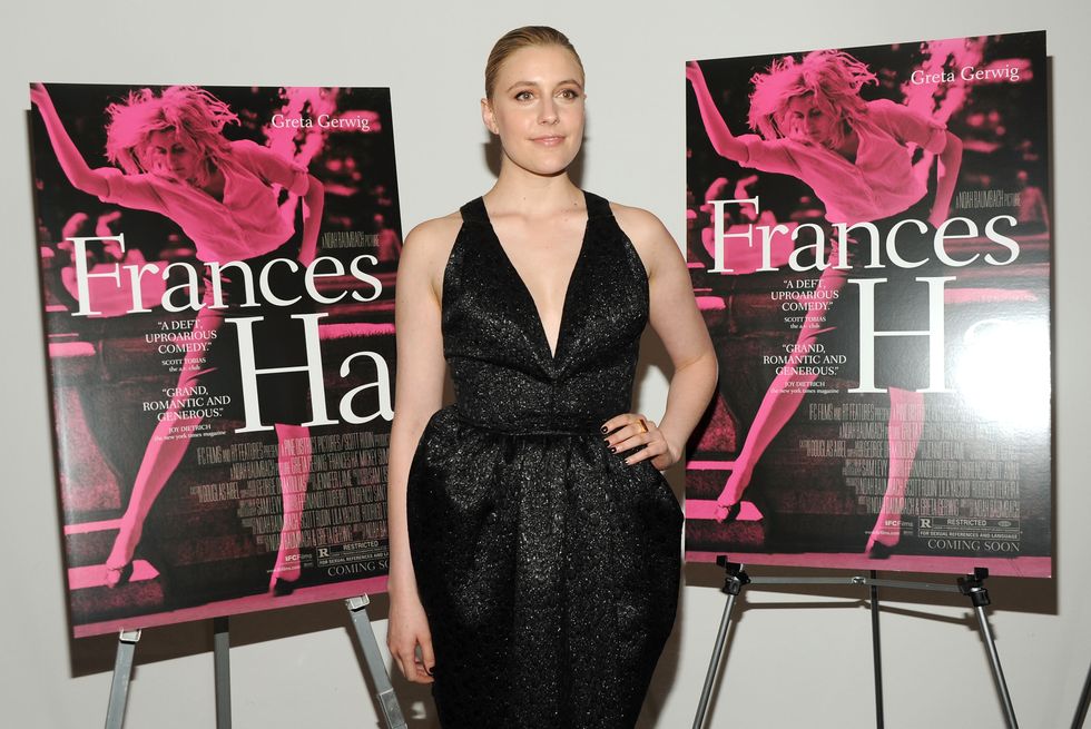 greta gerwig wearing a black dress, standing next to two posters for the film frances ha