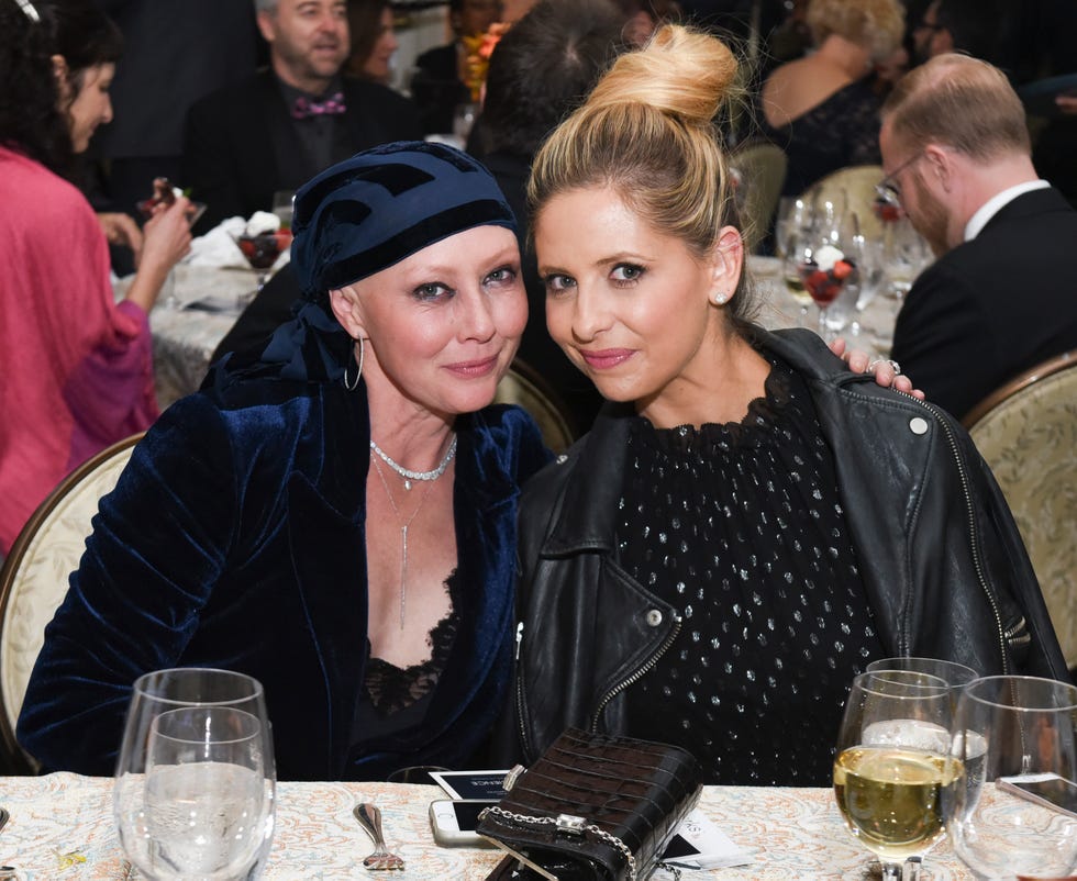 shannen doherty and sarah michelle gellar sitting together at a table and posing for a photo