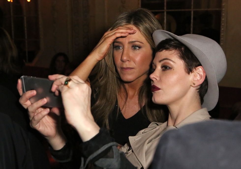 jennifer aniston poses for a selfie with a woman wearing a gray hat