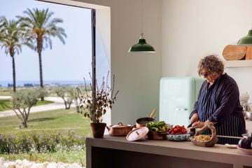 a person sitting at a table with a laptop and a basket of vegetables