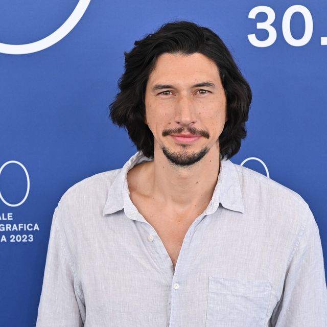 adam driver smiles at the camera while wearing a light colored button up shirt