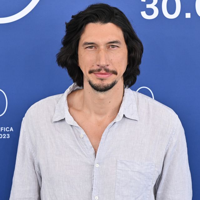 adam driver smiles at the camera while wearing a light colored button up shirt