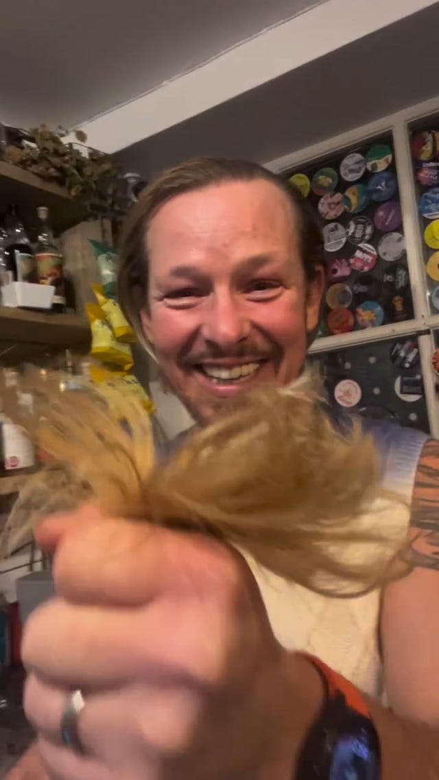 adam rickitt holds his hair after cutting it off